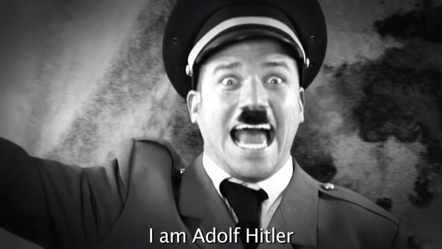 A picture of someone dressed as Adolf Hitler doing the Nazi-Salute saying “I am Adolf Hitler”