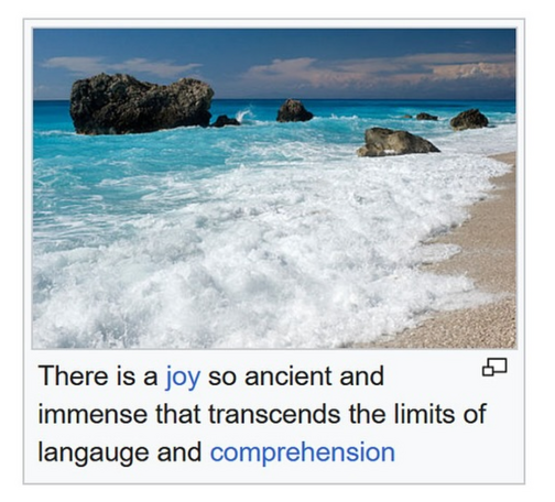 An image of large boulders and stones on a crystal blue beach with white foam waves breaking on the perfect sand beach