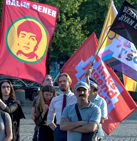 Ein Bild von Erik Uden in einer Menschenmenge mit Halim Dener und zwei Linksjugend ['solid] Flaggen im Hintergrund. Ich halte eine Flagge welche sagt „Widerstand heißt leben” auf Kurdisch.