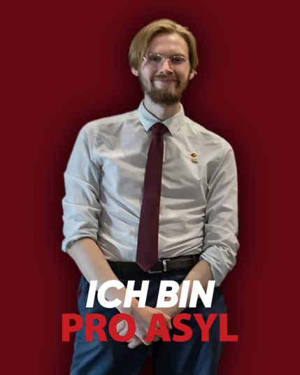 Ein Bild von Erik Uden mit Hemd und Krawatte, tragend mit Palästina- und Kuba-Pin, mit einem dunkelroten Hintergrund und dem Schriftsatz „Ich bin Pro Asyl”.