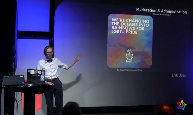 Ein Bild von Erik Uden vor einer Leinwand mit Teilen seiner Präsentation an der Wand. Er sieht professionell aus und trägt eine Fliege.