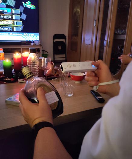 A picture of my father with a Nintendo Wii controller in his right and a bottle of rum in his left hand