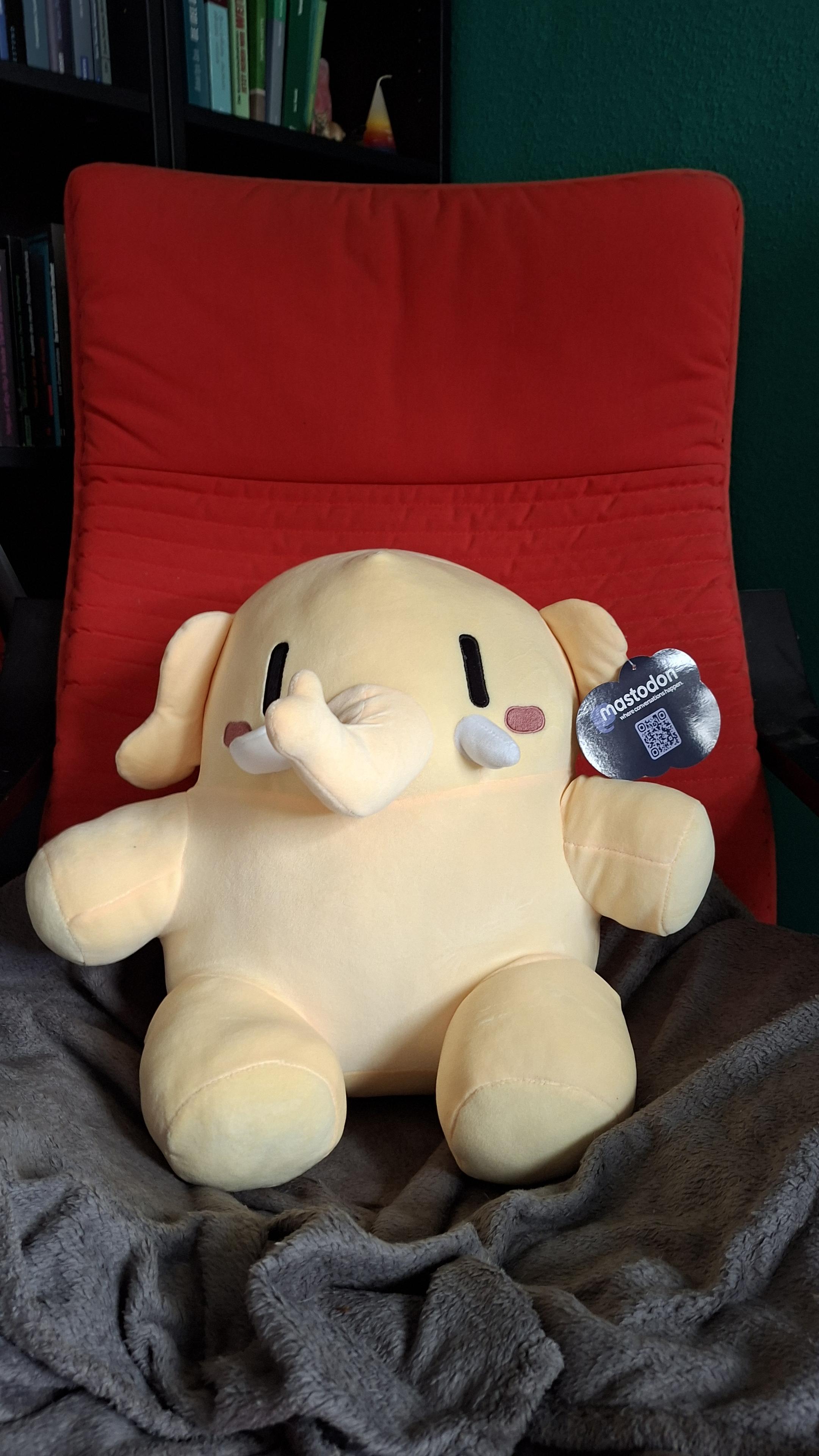 Das Bild zeigt ein Mastodon Plüschtier, dass auf einem Sessel sitzt.