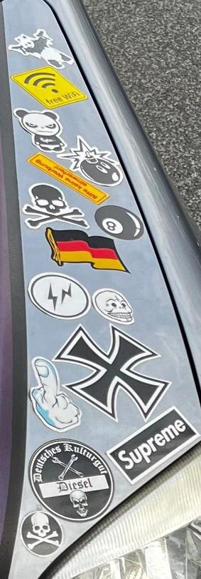 Ein Bild von Aufklebern auf einem Auto mit rechtsextremen Symbolen:

Aufzählung rechtsextremer Symbole / welchen die absichtlich verbotene Symbole umgehen mit kleinen Änderungen:

- SS Runen aber mit einer Rune verdreht
- Magic 8 Ball als Anlehnung an „HH” (Heil Hitler)
- SS-Totenkopf (aber ohne Knochen)