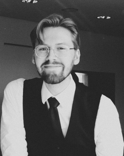 Ein Schwarz-Weiß Bild von Erik Uden vom 26. April 2026 auf der Landesmitgliederversammlung der Linksjugend ['solid] Niedersachsen wie er in die Kamera guckt. Das Bild wurde geschossen von Henry Matteo Bruder und gehört ihm auch, es ist frei verwendbar unter der CC-BY.