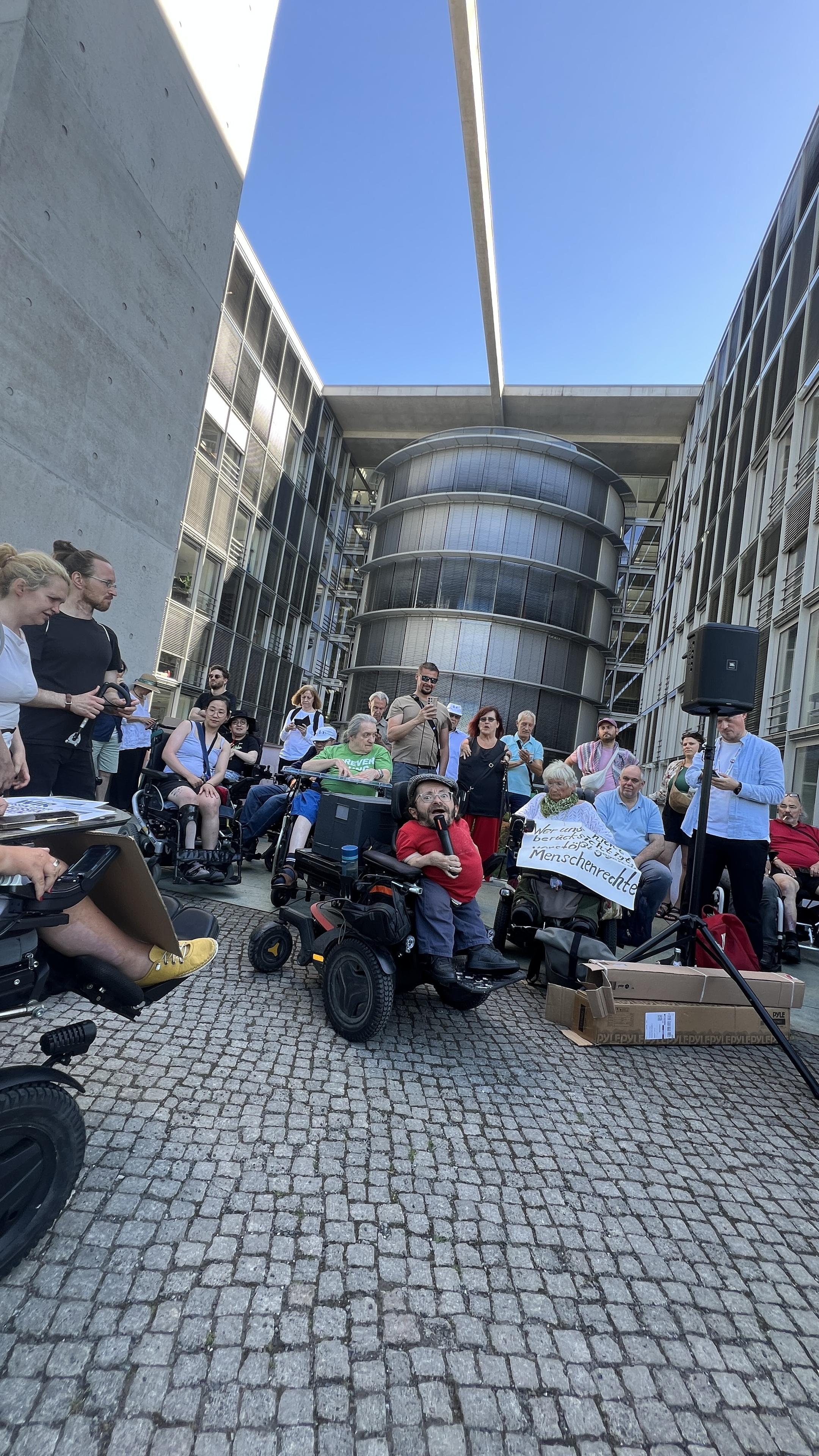 Demo vor dem Saal, Rau krauthausen spricht ins Mikrofon